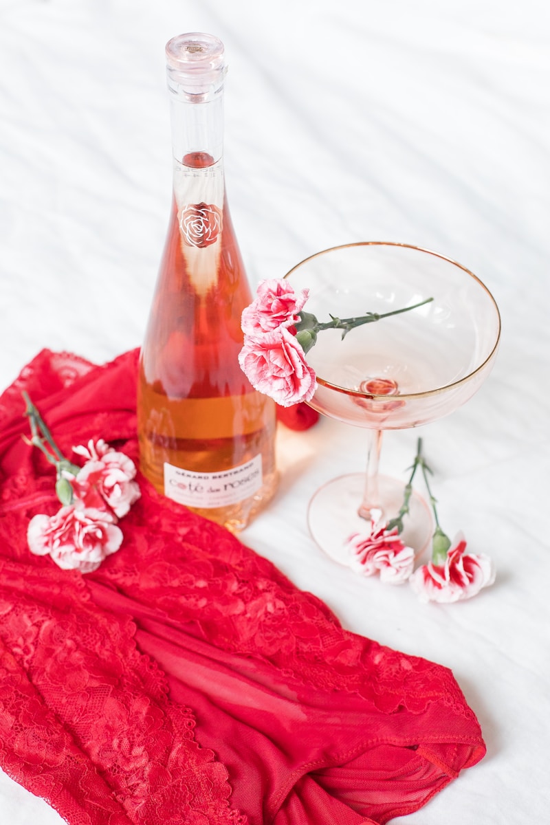 wine bottle near flowers on white textile